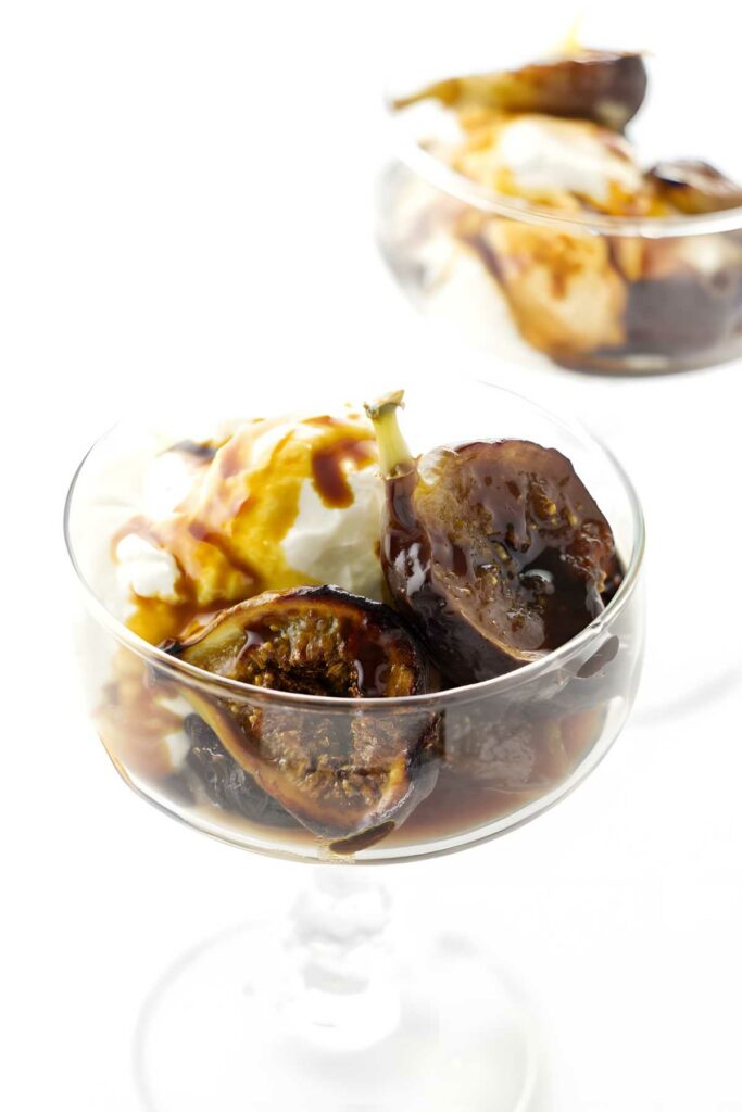 A dish with caramelized figs spooned over vanilla ice cream. 