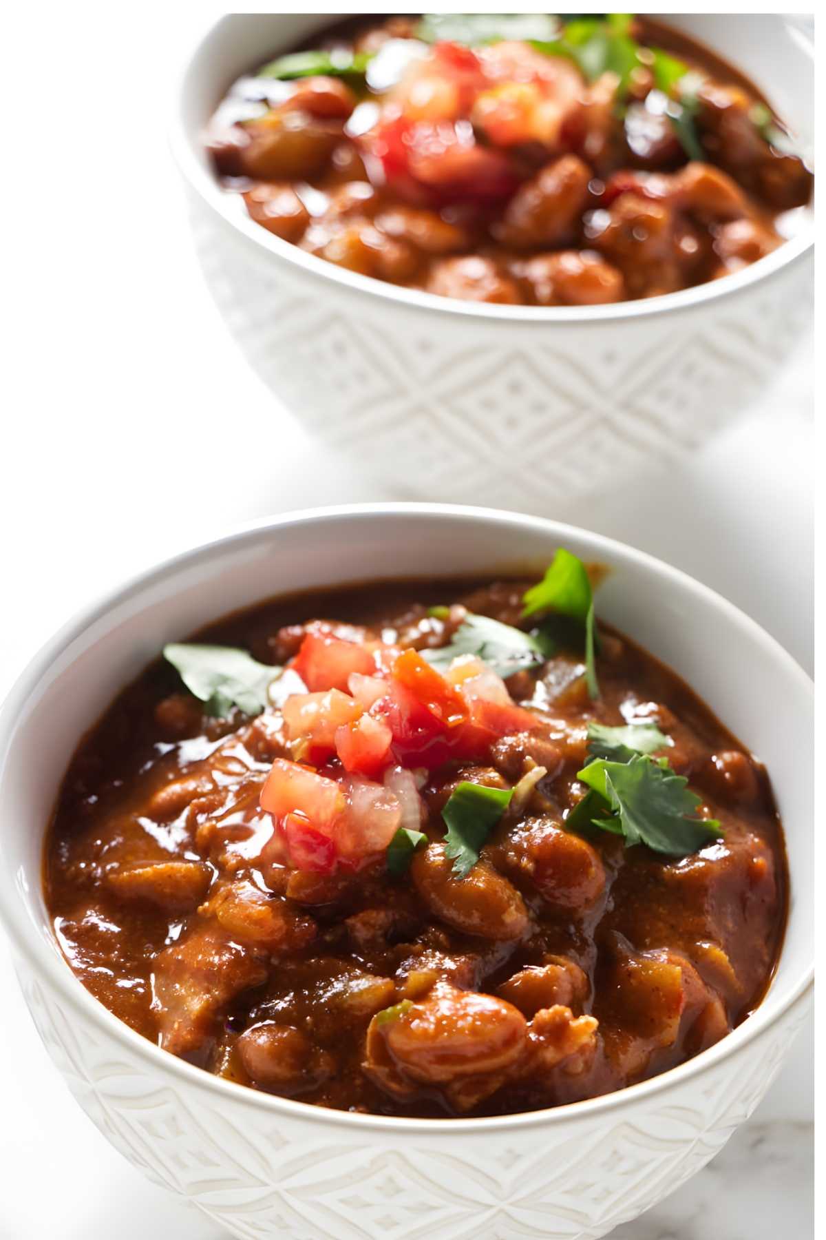Two bowls of charro beans on a counter.