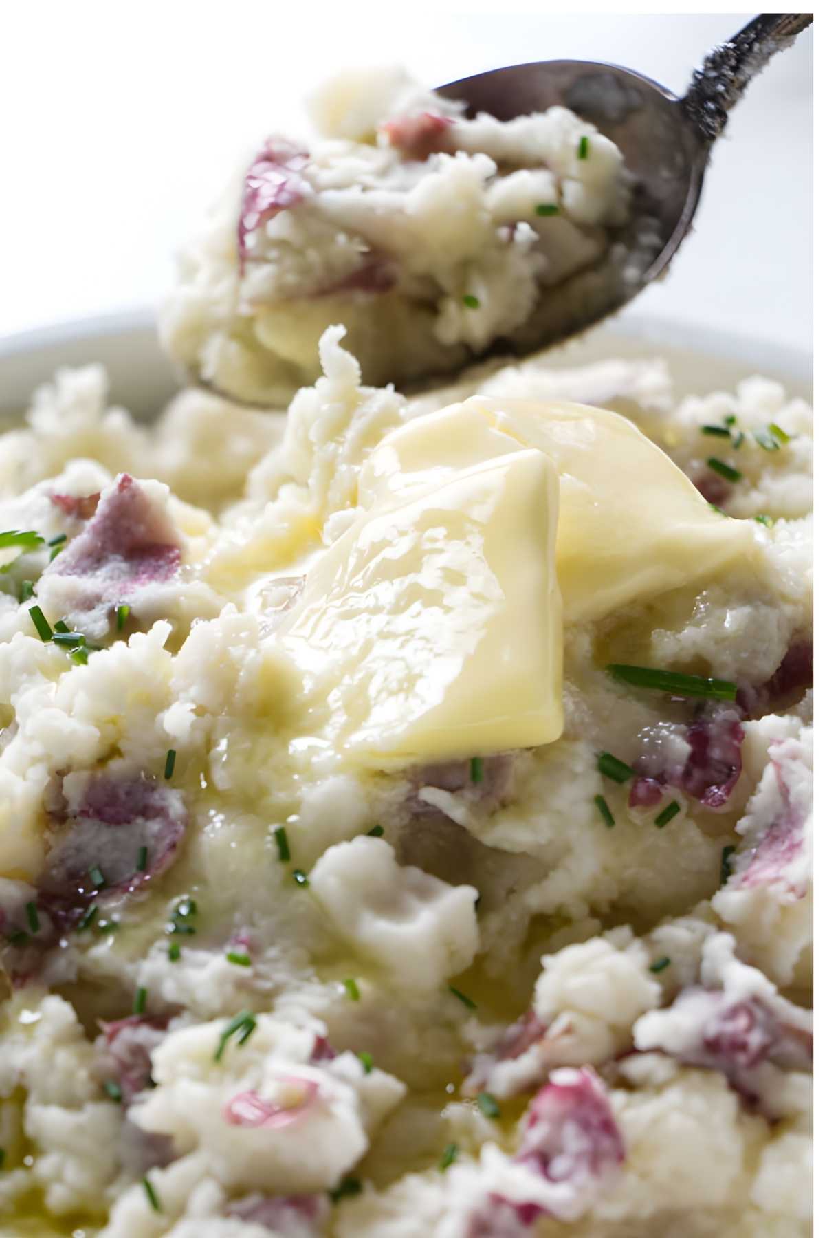 A spoon scooping red mashed potatoes from a bowl.