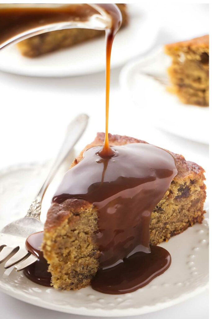 Slice of date cake on plate with fork, topped with caramel sauce.