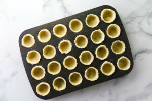 Placing dough in mini muffin tin to make tassies.