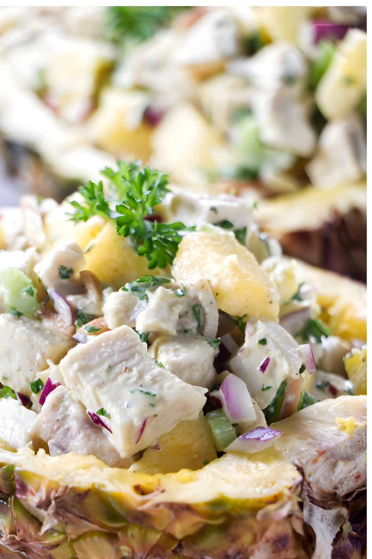 Chicken salad with pineapple and herbs served in a hollowed-out pineapple shell.