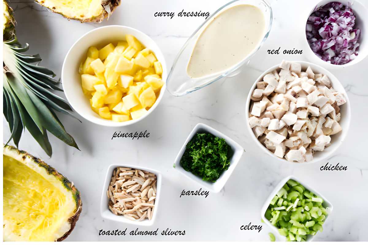 Overhead shot of six labeled bowls with chicken, pineapple, veggies, nuts, and dressing.