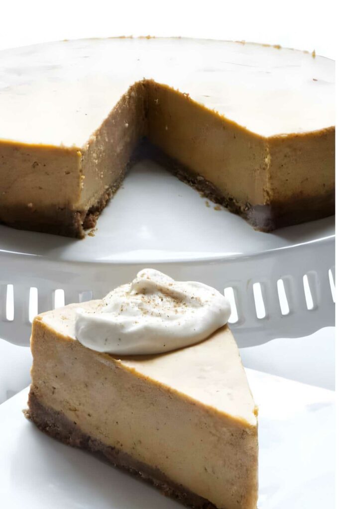 Pumpkin spice cheesecake slice with whipped cream on plate, whole cake behind, wedge missing.