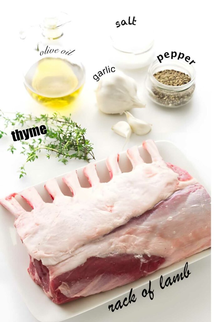 Raw rack of lamb on tray with herbs, garlic, oil, pepper, and salt.