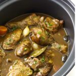 Chicken, carrots, and garlic simmer in a slow cooker.