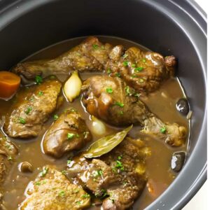 Chicken, carrots, and garlic simmer in a slow cooker.
