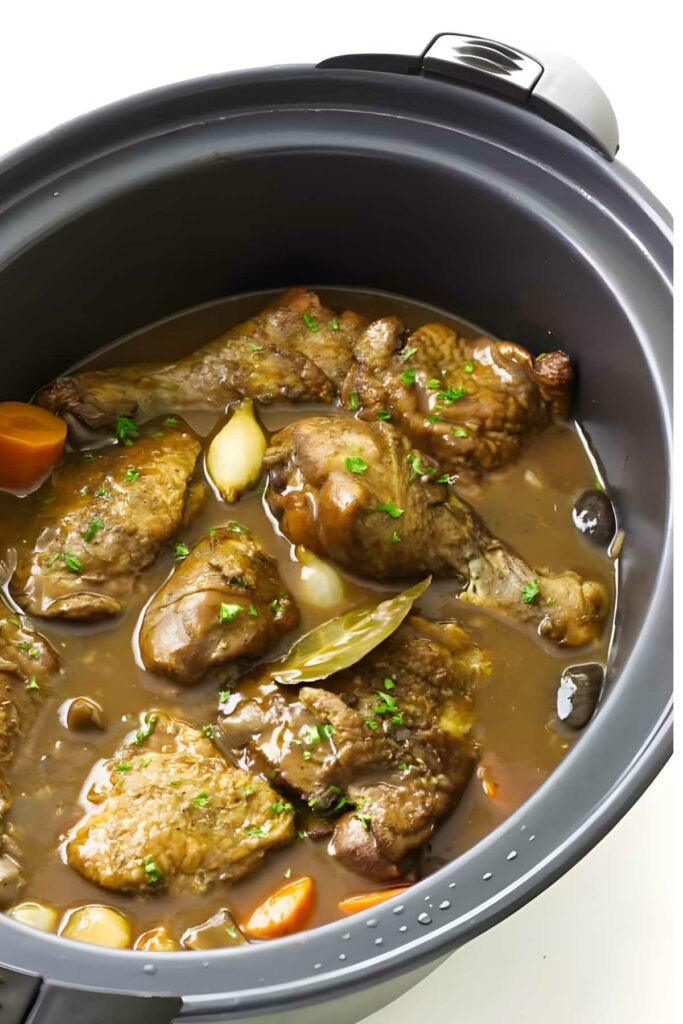 Chicken, carrots, and garlic simmer in a slow cooker.