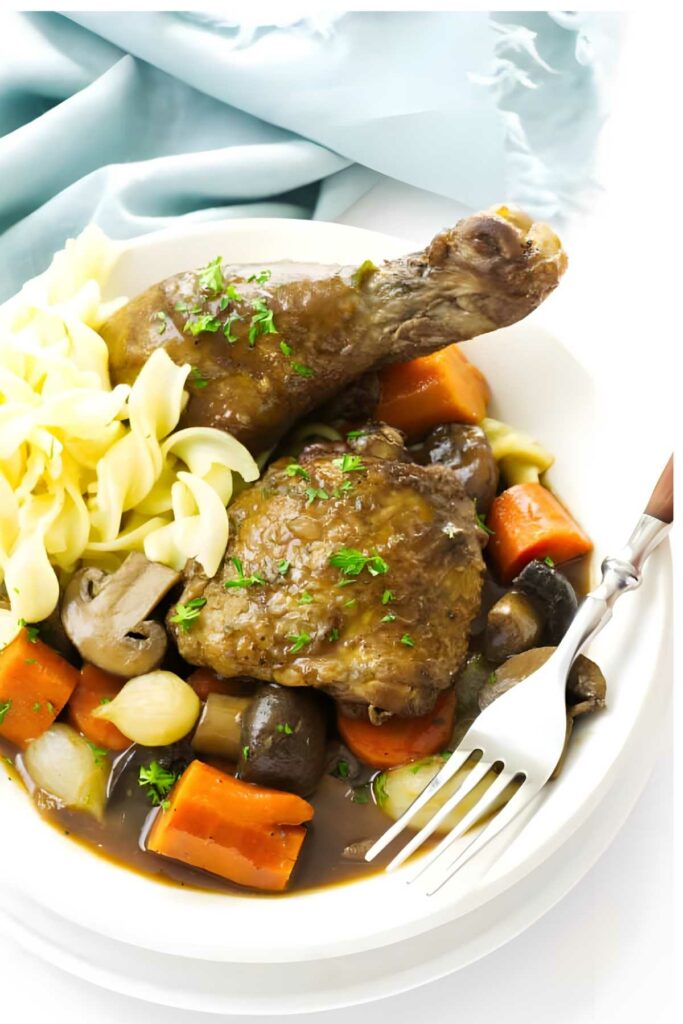 Slow cooker chicken with noodles, vegetables, and sauce on a plate with a fork.