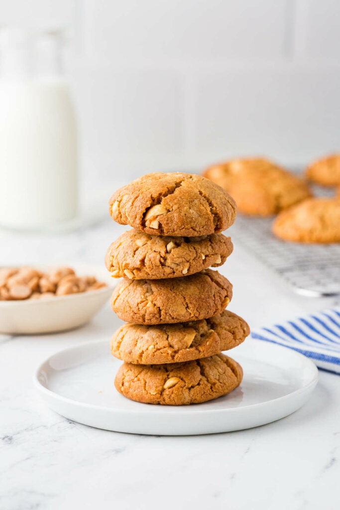 A stack of sourdough peanut butter cooies in front of a glass of milk.