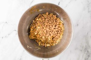 Adding peanut butter chips and chopped peanuts to cookie dough.