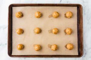 Placing balls of cookie dough on a baking sheet.