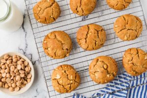 Peanut butter cookies cooling on a rack next to baking chips.