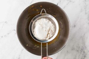 Sifting flour and baking powder into cookie dough.