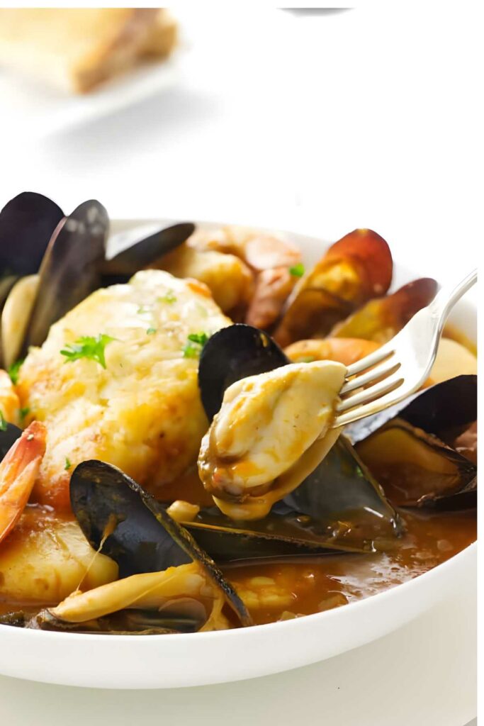 Fork lifts fish from hearty seafood stew with mussels and shrimp.