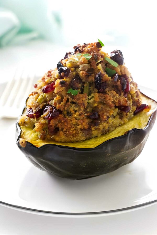Stuffed acorn squash with breadcrumbs and herbs on a white plate.