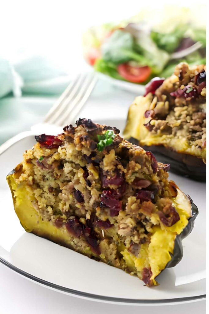 Stuffed acorn squash half with sausage and cranberries on a white plate.