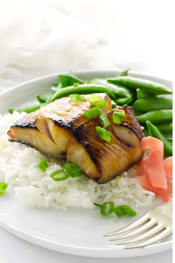 Glazed fish on rice with green onions, green beans, and pickled ginger.