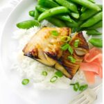 Grilled fish on rice with green onions, snap peas, and pickled ginger.