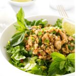 Minced chicken salad with herbs in a white bowl, lime garnish.