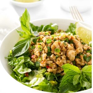 Minced chicken salad with herbs in a white bowl, lime garnish.