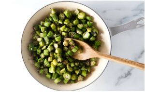 Diced okra in a skillet with a wooden spoon.