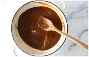 Cooking a roux in a skillet until it is deep brown in color.