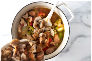 Adding chicken and sausage back to the pot of gumbo.