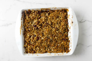 Freshly baked recipe for apple crisp in a white baking dish.