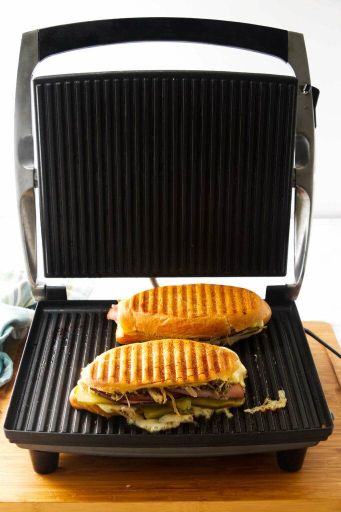 A pressed Cuban sandwich in a panini press.