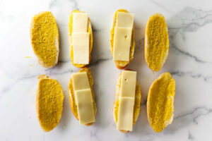 Adding mustard and cheese to soft bread rolls.