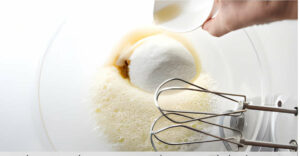 Adding sugar and vanilla to the egg mixture.