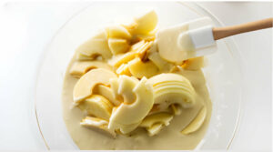 Stirring sliced apples into the batter.