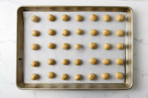 Balls of Italian Christmas cookie dough on a sheet pan.