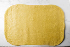 Pumpkin yeasted dough rolled out on a counter.