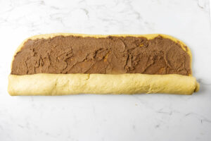 Rolling pumpkin spice roll dough into a log.