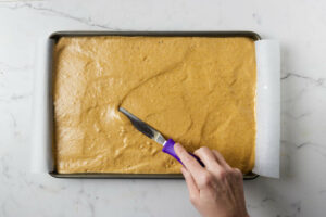 Spreading the pumpkin cake batter into a jelly roll cake pan.