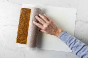 Rolling the warm pumpkin cake into a log.