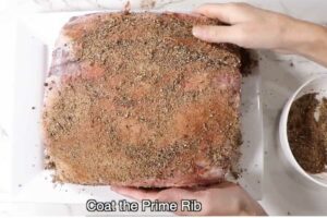 Covering the prime rib with a dry rub.