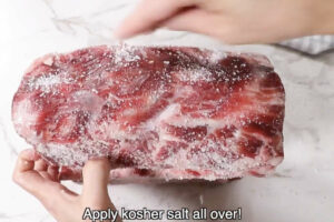 Applying kosher salt to prime rib.