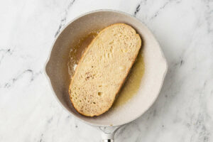 Cooking a slice of sourdough french toast in a skillet.