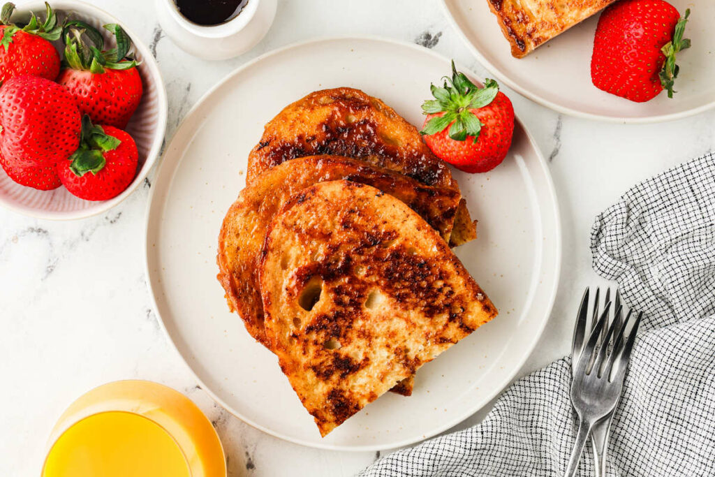 A breakfast plate filled with french toast with sourdough bread and berries.