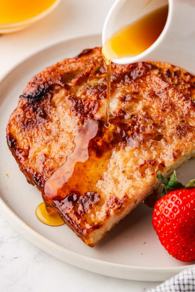 Pouring syrup over a slice of french toast.