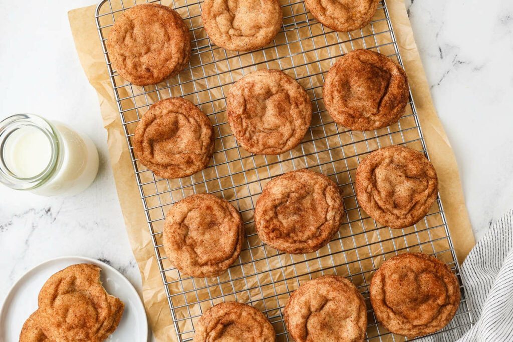 Sourdough snickerdoodle cookies on a rack next to a glass of milk.