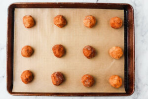Balls of snickerdoodle cookie dough on a baking sheet.