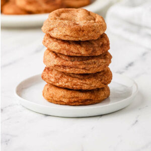 A stack of snickerdoodles on a white dessert plate.