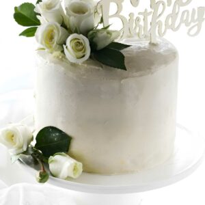 White cake with white roses and Happy Birthday sign on cake stand.
