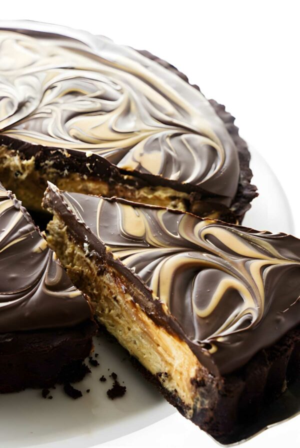 Close-up of marbled chocolate peanut butter tart, one slice served on a white plate.