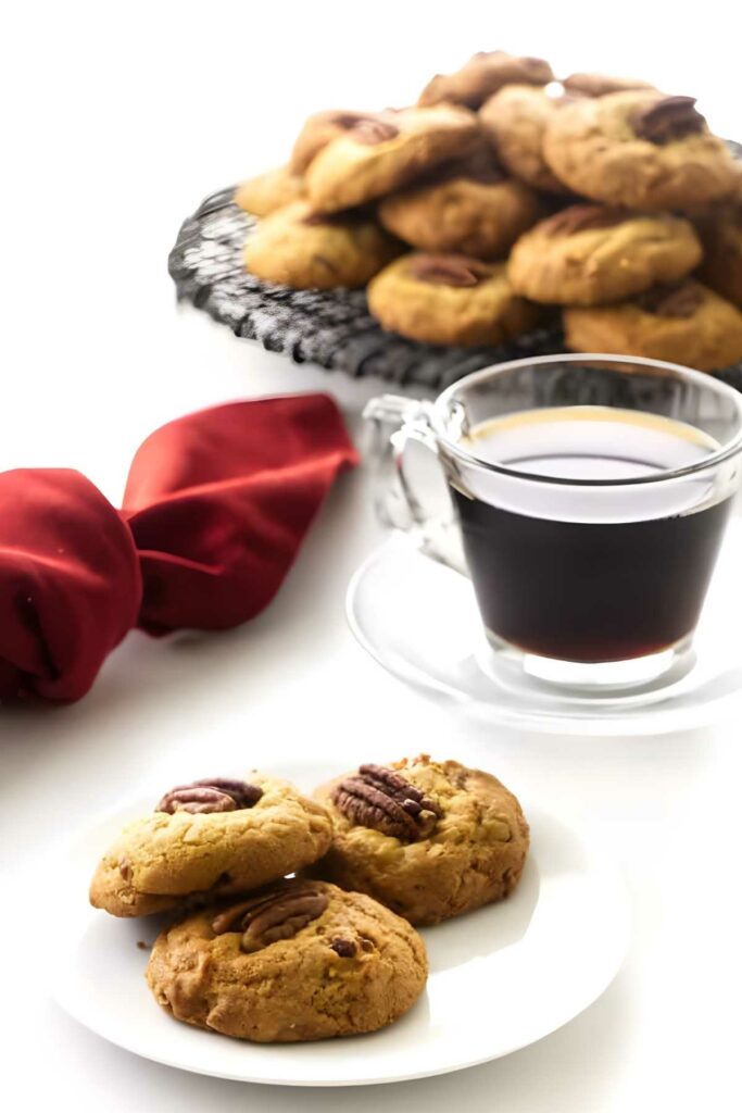 Three pecan coconut cookies next to a cup of coffee.