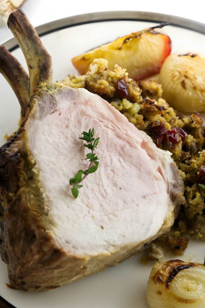 Bone-in pork roast with thyme, stuffing, cranberries, roasted onion, and apple.